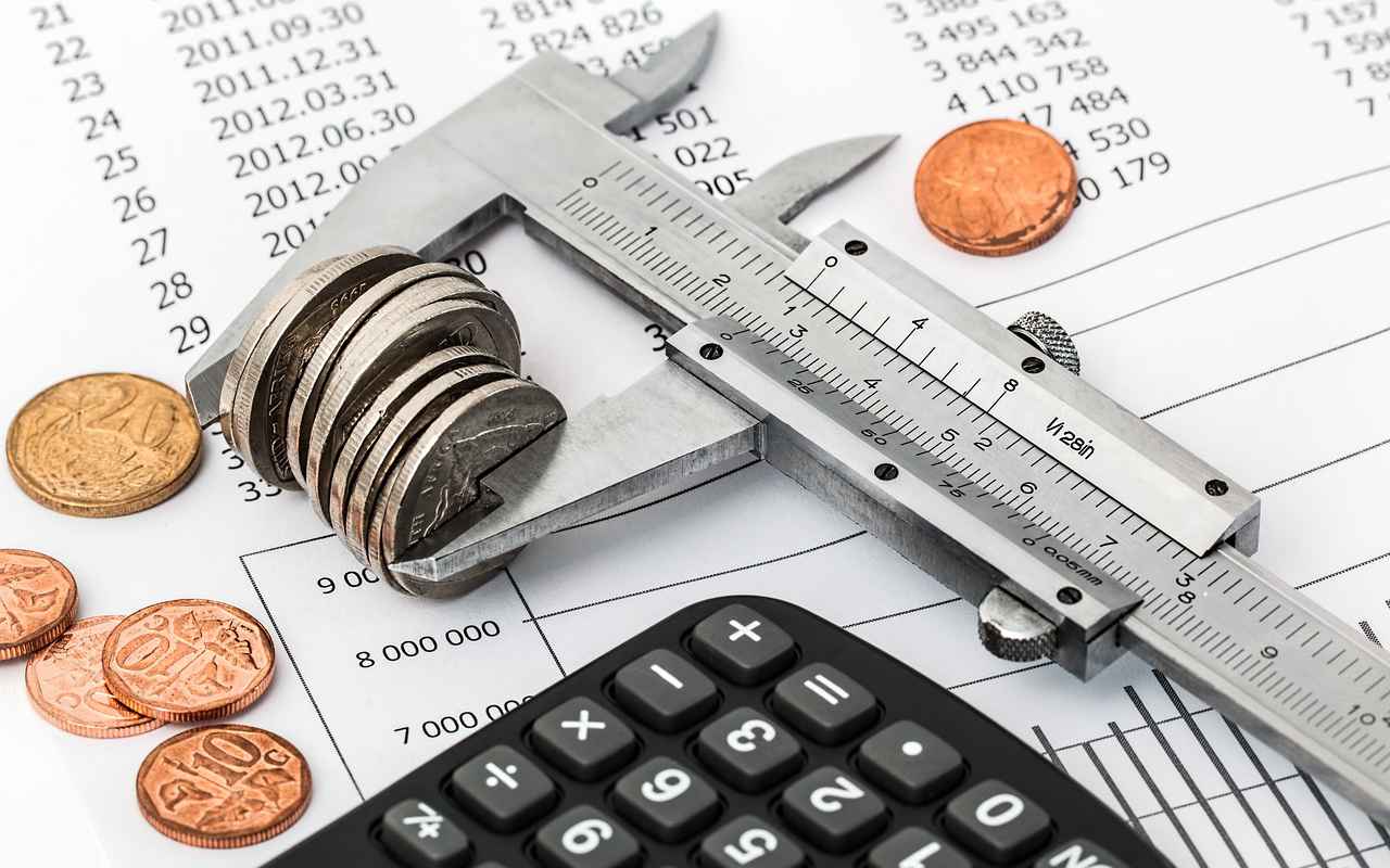 Screw clamp in which coins are clamped on a sheet of paper and a calculator.