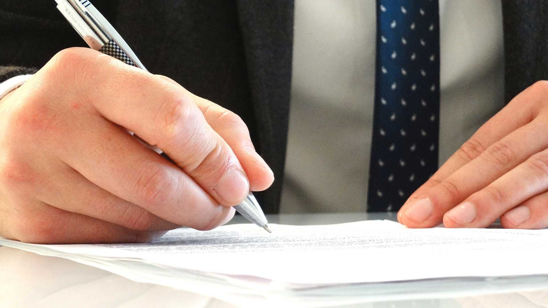 A man in a suit signs a document.