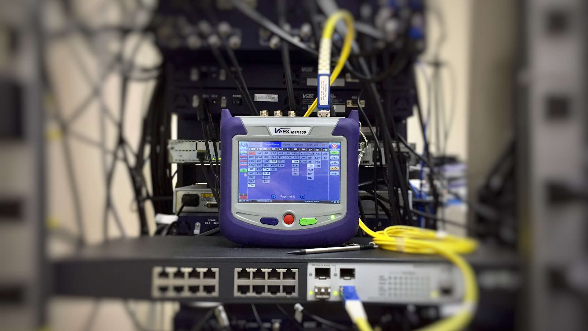 Netzwerk-Meßgerät steht auf einem Netzwerk-Hub/Switch.