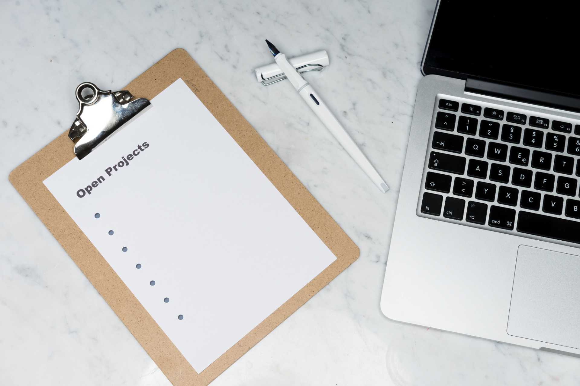 Laptop, pen, and a clipboard with a piece of paper that says Open Projects.